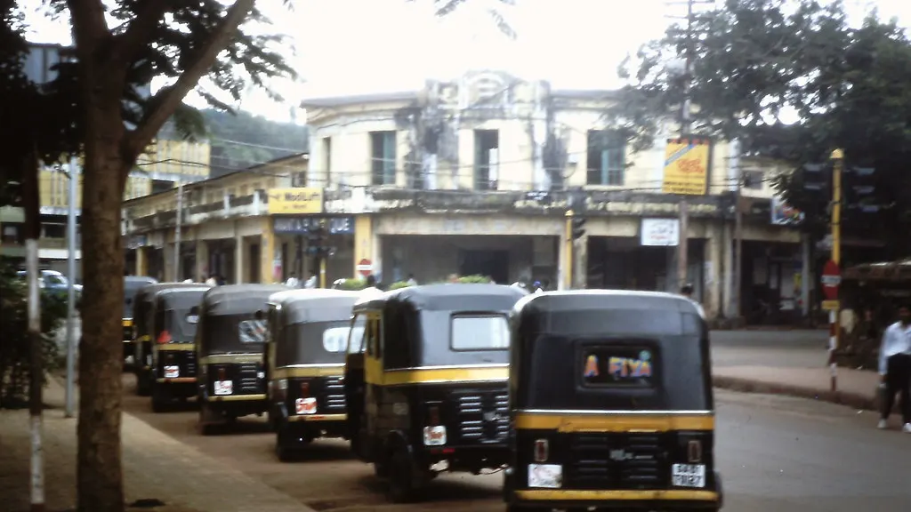 Bajaj auto-rickshaw taxis lined up at a stand on a street in Goa