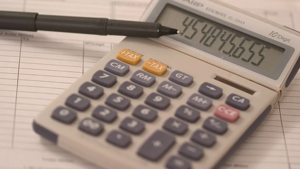 A calculator and pen resting on a paper ledger