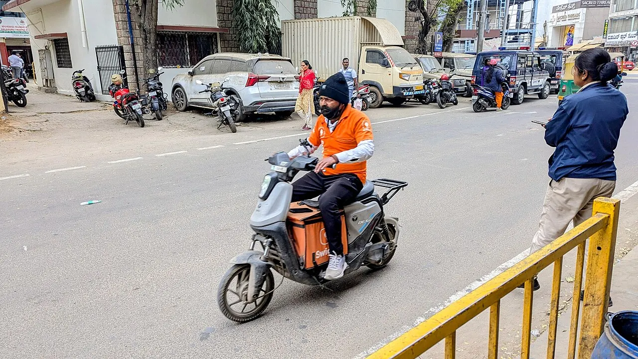 A delivery partner riding a scooter on a city street in Bengaluru
